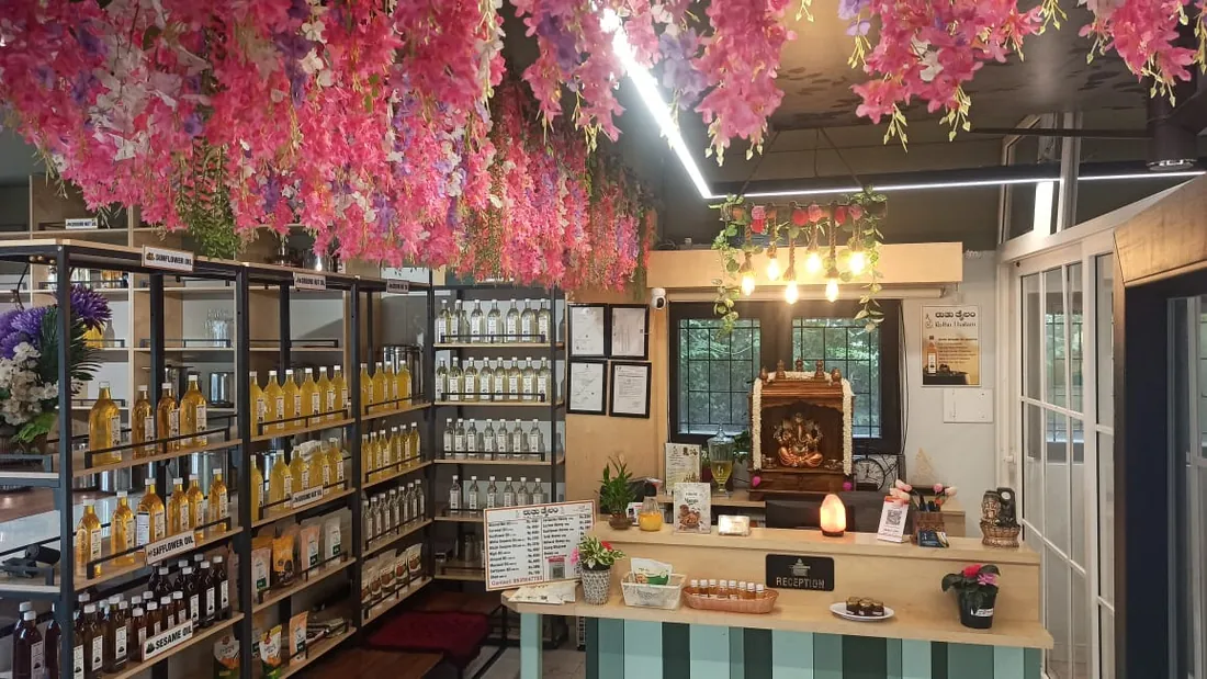 Inside the Ruthu Thailam store in Thippasandra, shelves of wood-pressed oil bottles under hanging flowers